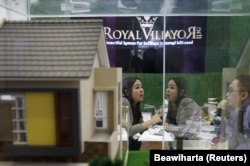 Seorang agen real estate (kiri) berbincang dengan pelanggannya di samping model properti saat Indonesia Property Expo 2016 di Jakarta, 16 Februari 2016. (Foto: REUTERS/Beawiharta)