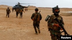 FILE - Iraqi Special Forces members board a helicopter during the "Solid Will" military operation against Islamic State militants in the desert of Anbar, Iraq, April 23, 2022. 