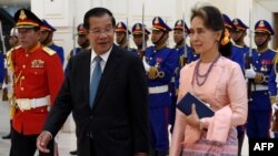 Aung San Suu Kyi (kanan) dan Perdana Menteri Kamboja Hun Sen berjalan melewati penjaga kehormatan selama kunjungannya di Istana Perdamaian di Phnom Penh, 30 April 2019. Junta Myanmar pada 8 Mei menolak permintaan Hun Sen untuk melakukan pembicaraan dengan Suu Kyi. (Foto: AFP)