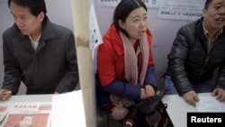 资料照片: 2016年2月23日招聘人员在中国北京招聘会上与求职者交谈