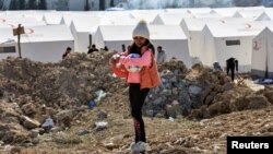 A girl holding sports balls stands at a camp for survivors, in the aftermath of the deadly earthquake, in Adiyaman, Turkey, Feb. 18, 2023.
