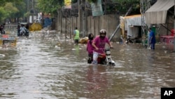 Motorcyclists ride through a flooded street after a heavy rainfall in Lahore, Pakistan, July 1, 2024.