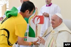Pope Francis receives a JMJ (WYD) plaque from a volunteer during the closing mass of the World Youth Days (WYD) in Tejo Park, Lisbon, Aug. 6, 2023. (Photo by Handout / Vatican Media / AFP)