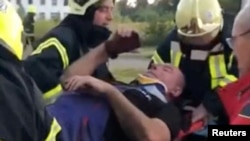 Ukrainian rescuers carry a man on a stretcher after he was pulled out from under the rubble, following a Russian missile strike in the location given as Lutsk, Ukraine in this image from a social media video released on Aug. 15, 2023.