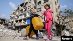 Anak-anak Palestina berjalan melewati sebuah bangunan yang rusak akibat serangan Israel, di tengah konflik yang sedang berlangsung antara Israel dan Hamas, di Rafah, di selatan Jalur Gaza, 1 Mei 2024. (Foto: Reuters)