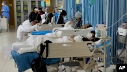 FILE - People attend to relatives receiving medical treatment at a hospital in Beijing, Jan. 7, 2023. Rising premiums and reduced benefits are two of the factors behind a drop in the number of Chinese enrolled in the basic government-run health plan.