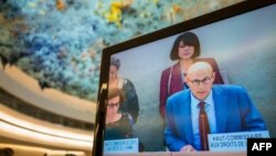 UN High Commissioner for Human Rights Volker Türk appears on a TV screen as he delivers a speech at the opening of the 54th UN Human Rights Council in Geneva, Sept. 11, 2023. 