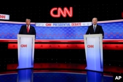 Presiden Joe Biden, kanan, dan calon presiden dari Partai Republik mantan Presiden Donald Trump, kiri, berdiri saat istirahat dalam debat presiden yang diselenggarakan oleh CNN, Kamis, 27 Juni 2024, di Atlanta. (Foto: AP)