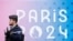 A French gendarme walks past the logo of the Paris 2024 Olympic and Paralympic Games in front of the National Assembly in Paris, May 2, 2024. 