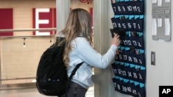 A ninth grader places her cellphone into a phone holder as she enters class at Delta High School, Friday, Feb. 23, 2024, in Delta, Utah. (AP Photo/Rick Bowmer)