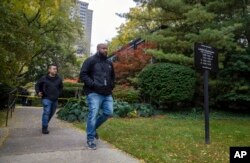 Two law enforcement officers pass a police tape near the scene where a Detroit synagogue president, Samantha Woll, was found dead in Detroit, Oct. 21, 2023.