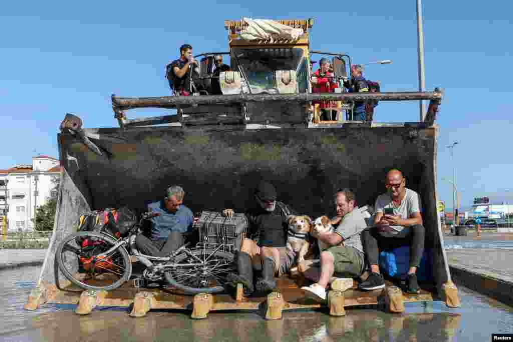 Locals are evacuated on an excavator from a flooded area, in the aftermath of Storm Daniel, in Larissa, Greece, Sept. 10, 2023. 
