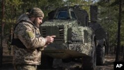 FILE - A Ukrainian soldier checks his phone while standing in front of a Swedish self-propelled Archer howitzer system at the front line in Ukraine's Donetsk region, March 4, 2024.