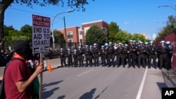 Police walk towards protesters who knock down a fence surrounding United Center at the Democratic National Convention after a march, Aug. 19, 2024, in Chicago.