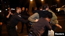 A police officer detains one of the protesters during a demonstration, as Israeli Prime Minister Benjamin Netanyahu's nationalist coalition government presses on with its contentious judicial overhaul, in Tel Aviv, Israel, March 18, 2023.