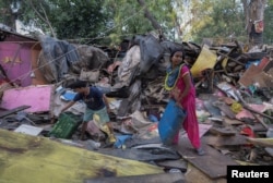 FILE - Dharmender Kumar and his wife Khushboo Devi collect usable items from the rubble of their house during a demolition drive by the authorities at a slum area near the upcoming summit venue in New Delhi, June 1, 2023.
