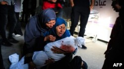 Seorang perempuan Palestina mengendong jenazah seorang anak yang tewas dalam pemboman Israel, di sebuah klinik kesehatan di kawasan Tel al-Sultan di Rafah, Jalur Gaza selatan, Minggu 26 Mei 2024. 