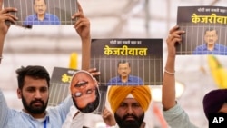 Supporters of the Aam Admi Party leader and Delhi Chief Minister Arvind Kejriwal hold posters at a protest organized by INDIA bloc, a group formed by opposition parties, in New Delhi, India, March 31, 2024. 