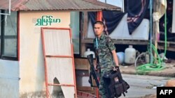 สมาชิกกลุ่มติดอาวุธเมียนมา ถืออาวุธข้ามแม่น้ำเมยจากฝั่งเมียนมา เห็นได้จาก อ.แม่สอด จ.ตาก ของไทย เมื่อ 11 เม.ย. 2024 (Photo by Manan VATSYAYANA / AFP)