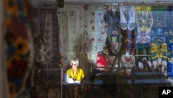 Prodavačica obasjava prostor baterijskom lampom tokom isključenja struje u podzemnom tržnom centru u centru Kijeva, Ukrajina, 19. juna 2024.