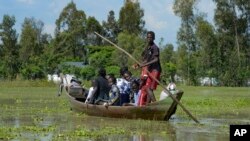 FILE - A family uses a canoe after fleeing floodwaters that wreaked havoc in Ombaka Village, Kisumu, Kenya, April 17, 2024. 