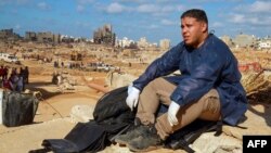 A volunteer sits on the rubble of a building in a flash flood-damaged area in Derna, Libya, on Sept. 14, 2023.