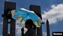 นักท่องเที่ยวที่มาเยือนกรุงวอชิงตันรายนี้ เดินกางร่ม ท่ามกลางสภาพอากาศที่รุนแรงจากคลื่นความร้อน เมื่อ 19 มิ.ย. 2567