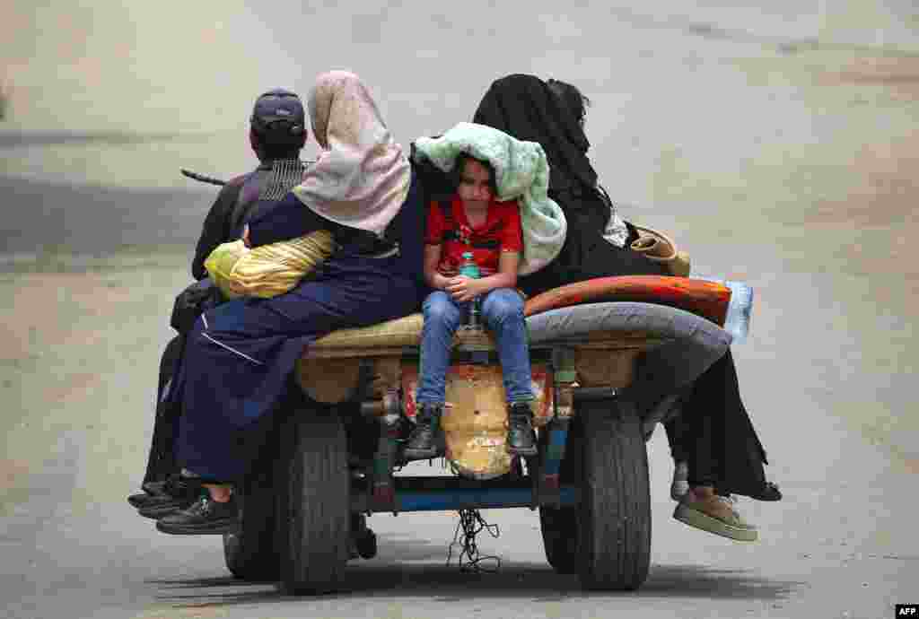 Palestinians sit on an animal pulled cart as they move to safer areas in Rafah, in the southern Gaza Strip, amid the ongoing conflict between Israel and the militant group Hamas.
