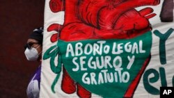 FILE - A woman holds a banner reading in Spanish, 'Legal, safe, and free abortion' as abortion rights protesters demonstrate in Mexico City, Sept. 28, 2020.