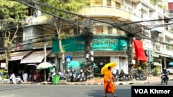 A monk walks in front of a branch office of Amret Microfinance Institution in Daun Penh district, Phnom Penh, Cambodia’s capital, April 5, 2024. (Sun Narin/VOA Khmer)
