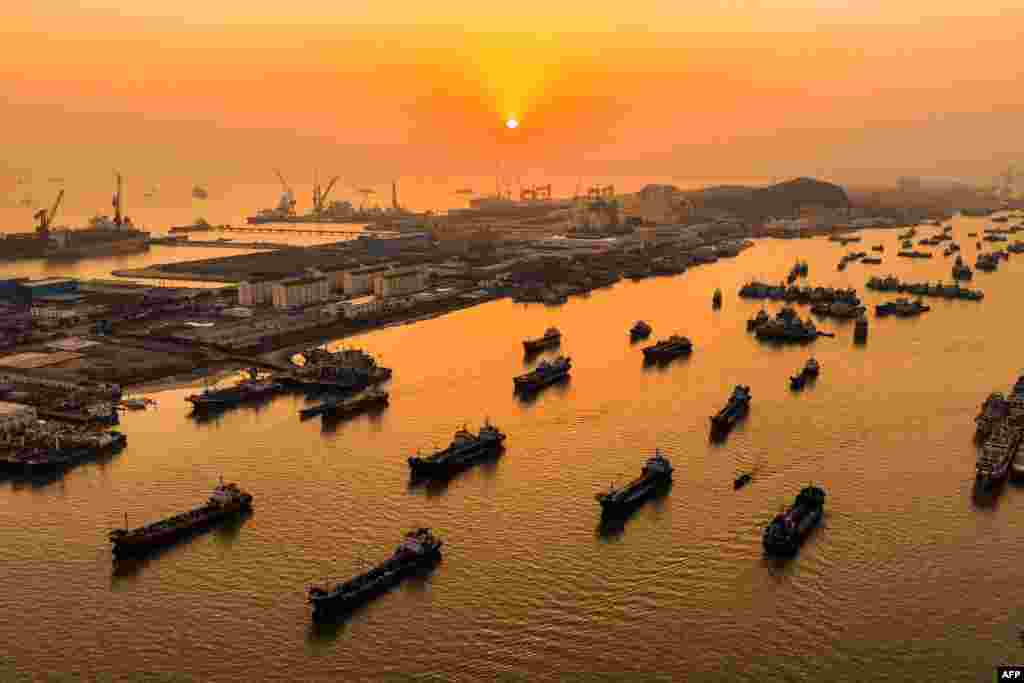Fishing boats sail around Shenjiamen Fishing Port during sunset in Zhoushan, in eastern China's Zhejiang province, March 20, 2024.