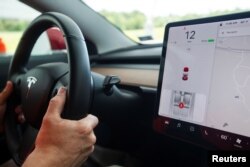 FILE - Joe Young, media relations associate for the Insurance Institute for Highway Safety, demonstrates a front crash prevention test on a 2018 Tesla Model 3 at the IIHS-HLDI Vehicle Research Center in Ruckersville, Virginia, July 22, 2019.