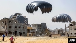 Orang-orang berlarian untuk mengambil paket-paket bantuan yang dikirim lewat udara di utara Jalur Gaza, 23 April 2024. (Foto: AFP)