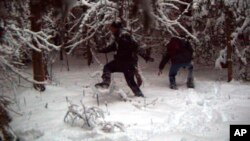 FILE - In this surveillance image provided by the United States Border Patrol Swanton sector, two individuals illegally cross the U.S./Canada border during January 2023 in the Vermont, New Hampshire and New York enforcement sector. 