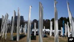 Artists perform on stage surrounded by decorations of 'peace flags' to commemorate victims of the earthquake and tsunami in the Tohoku region 12 years ago, during an anniversary event at Hibiya Park in Tokyo, March 11, 2023.