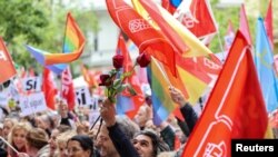 A man holds a rose as people gather outside Spain's Socialist Party headquarters to show support for Prime Minister Pedro Sanchez in Madrid, April 27, 2024. 