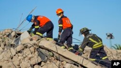 Rescue personnel search the site of a building collapse in George, South Africa, May 9, 2024. 