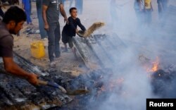 27일 밤 사이 이스라엘 군의 공습으로 화재가 난 가자지구 남부 라파의 난민 수용시설에 아직 꺼지지 않은 화재를 진압하는 팔레스타인 난민들.