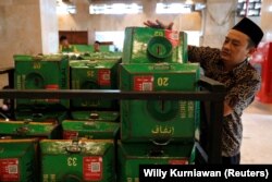 Seorang relawan mengumpulkan kotak sedekah dengan kode QR dan menumpuknya di gerobak setelah sholat Jumat di Masjid Istiqlal di Jakarta, 14 Februari 2020. (Foto: REUTERS/Willy Kurniawan)