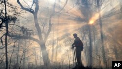 FILE -A member of the Bridge Crew watches over a fire line, Jan. 6, 2010, in case the prescribed burn jumps the line and ignites on the other side of Kings Pinnacle in Crowders Mountain State Park in Gastonia, NC. 