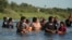 FILE - Migrants navigate around concertina wire along the banks of the Rio Grande after crossing from Mexico into the U.S., Aug. 1, 2023, in Eagle Pass, Texas. 