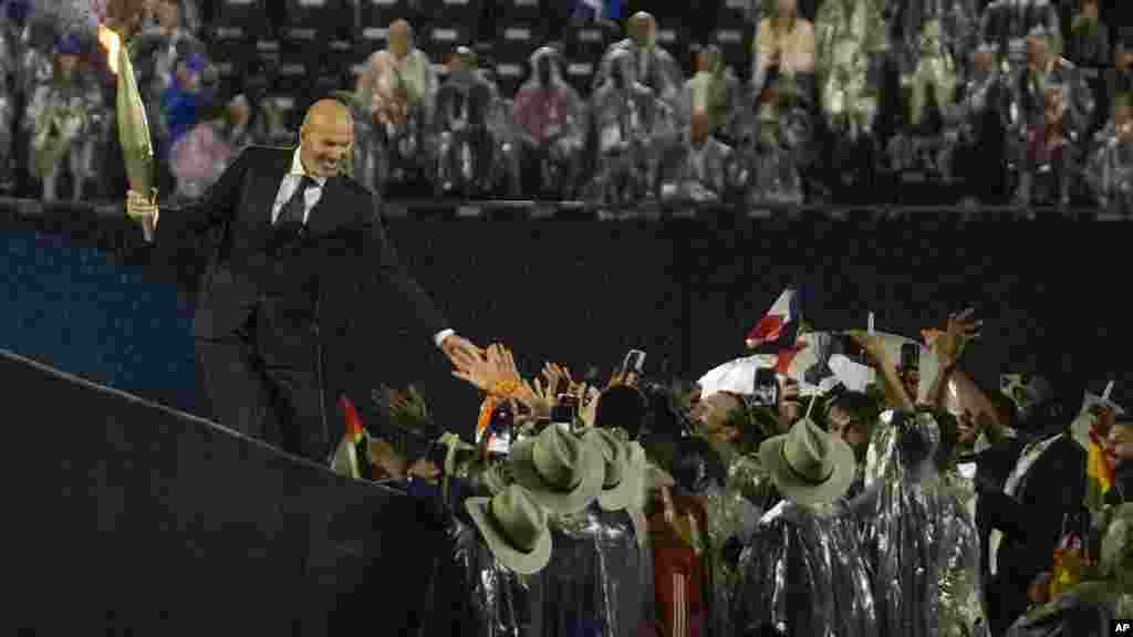 French soccer star Zinedine Zidane carries the torch during the opening ceremony of the 2024 Summer Olympics, July 26, 2024, in Paris.