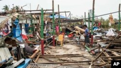Residents walk past damaged buildings in Sittwe township, Rakhine State, in the wake of Cyclone Mocha Myanmar, May 16, 2023. 