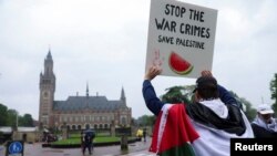 팔레스타인 국기를 두른 시위자가 국제사법재판소(ICJ) 밖에서 가자지구의 팔레스타인인들을 지지하는 팻말을 들고 있다. (자료사진)