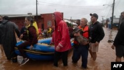 Residents and a dog are evacuated from a flooded area of Sao Sebastiao do Cai, Rio Grande do Sul State, Brazil, on May 2, 2024. 