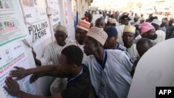Party agents look at a poster with polling station information in Kano, Nigeria, on Feb. 25, 2023, during Nigeria's presidential and general election. 