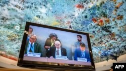 U.N. High Commissioner for Human Rights Volker Turk, center, is seen on a TV monitor speaking during a session of the 52nd U.N. Human Rights Council, in Geneva, on March 6, 2023. 