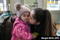 FILE - A refugee from the Ukrainian city of Mykolaiv, Anastasia Marunich, kisses her daughter Maria after fleeing the war from neighbouring Ukraine at a railway station in Przemysl, Poland, on Thursday, March 24, 2022. (AP Photo/Sergei Grits)
