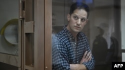 ນັກຂ່າວຂອງໜັງສືພິມ Wall Street Journal ທ່ານແອເວັນ ເກີສໂກວິຈ, ຜູ້ຖືກຈັບກຸມ ໃນຂໍ້ຫາ ການສອບແນມ, ຢືນຢູ່ພາຍໃນຄອກຂັງຂອງຈຳເລີຍ ໃນການພິຈາລະນາຮັບຟັງການຂໍອຸທອນ ກ່ຽວກັບການຈັບກຸມຂອງທ່ານ ຢູ່ທີ່ສານເມືອງຂອງມົສກູ, ໃນນະຄອນຫຼວງມົສກູ, ວັນທີ 18 ມີນາ 2023.