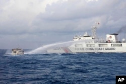 Garda Pantai China menembakkan meriam air ke arah kapal angkatan laut Filipina M/L Kalalayan yang mendekati beting Second Thomas Shoal di Laut China Selatan yang disengketakan, Minggu, 10 Desember 2023. (Foto: Garda Pantai Filipina via AP)